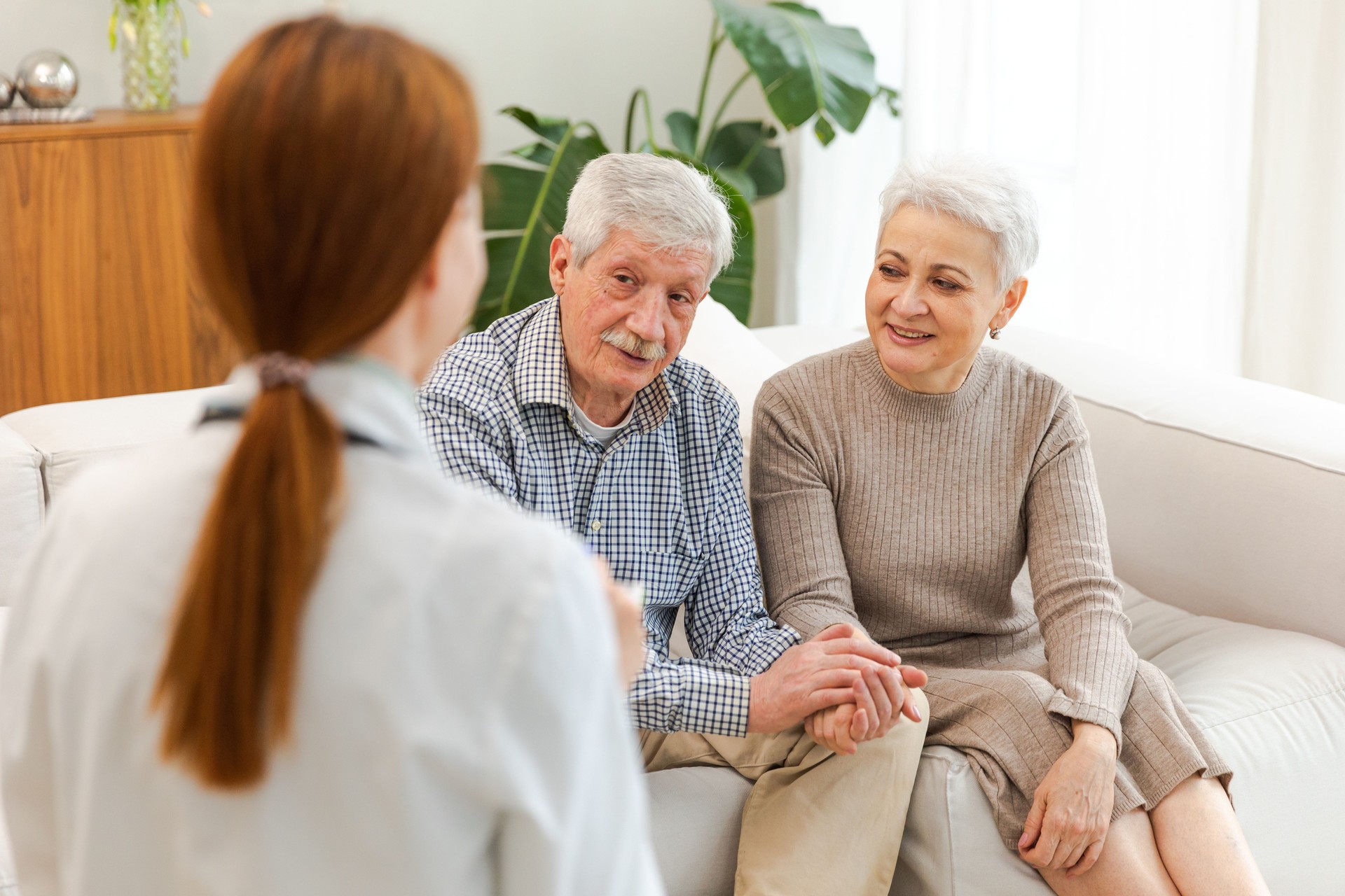 Female doctor examining older senior couple in doctor office or at home. Old woman man patient and doctor have consultation in hospital room. Medicine healthcare medical checkup. Visit to doctor.