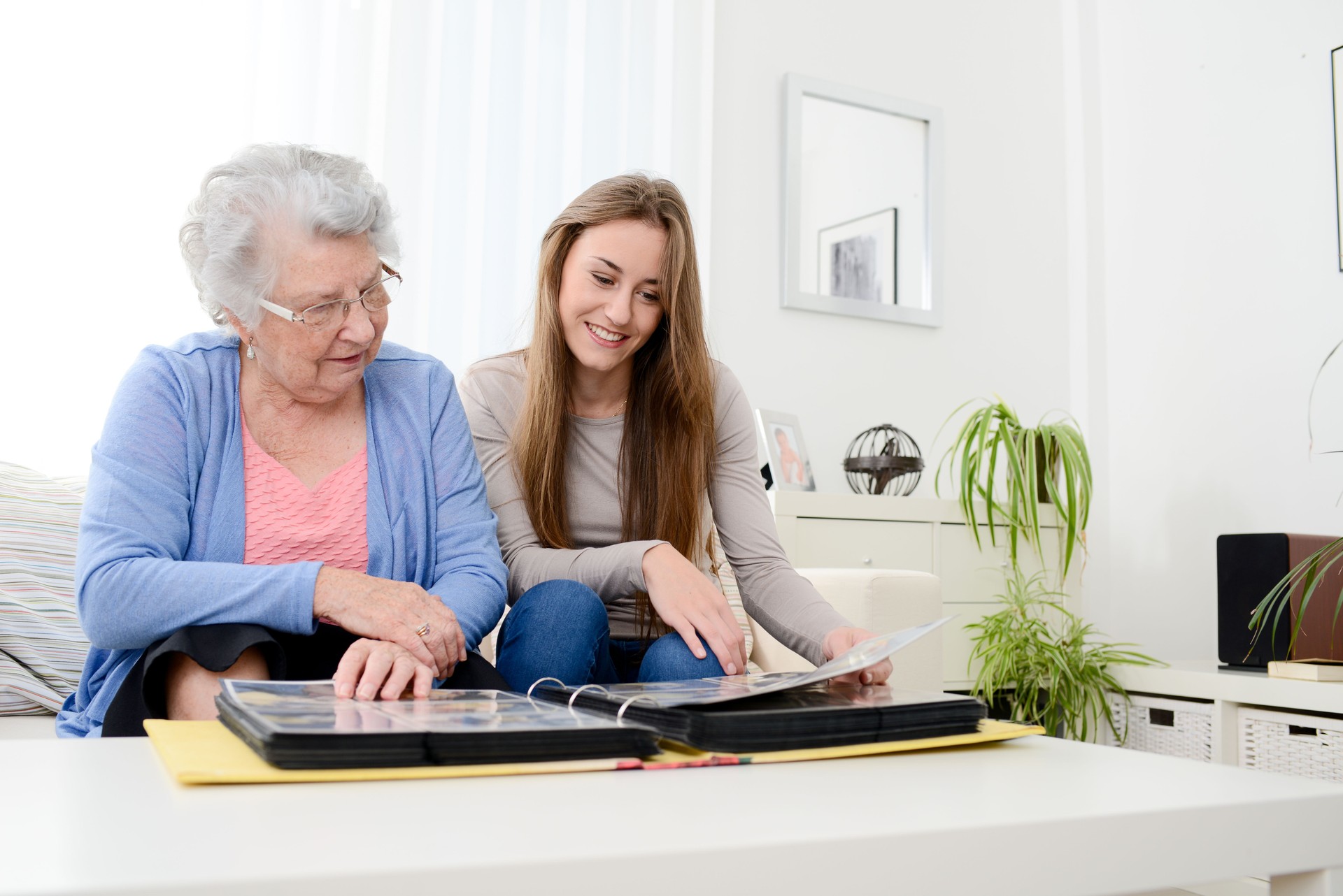 old senior woman with young granddaughter at home looking souvenir